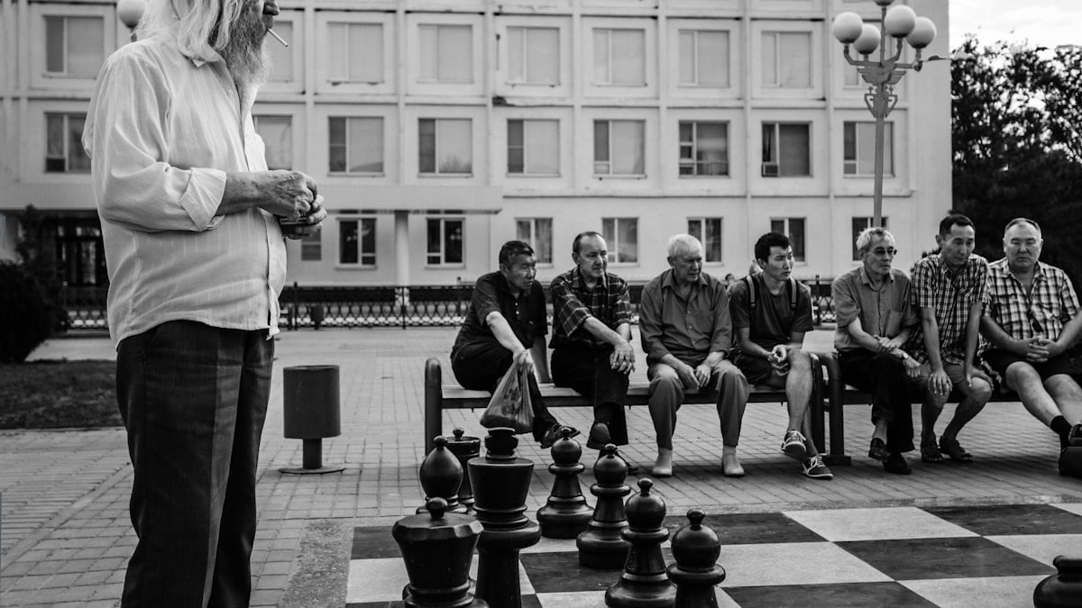 A black and white photo of people playing chess